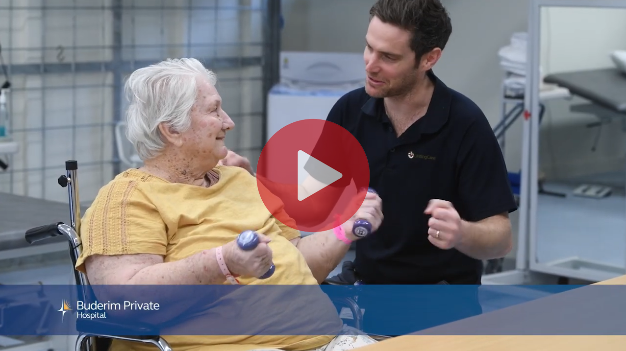 Older woman lifting weights as her male physio helps her